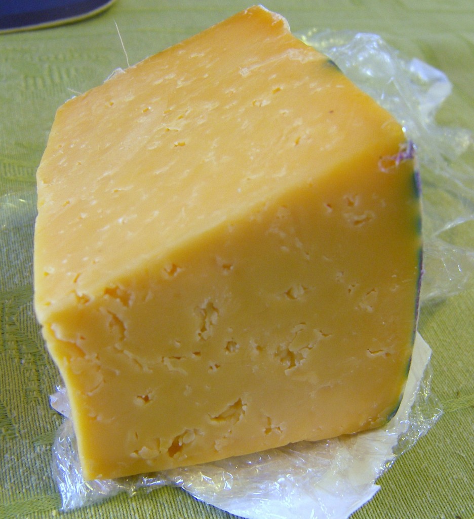 An upclose picture of a wedge of Pinconning cheese showing the little holes throughout