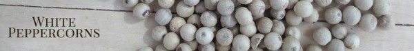 White peppercorns on a wood board