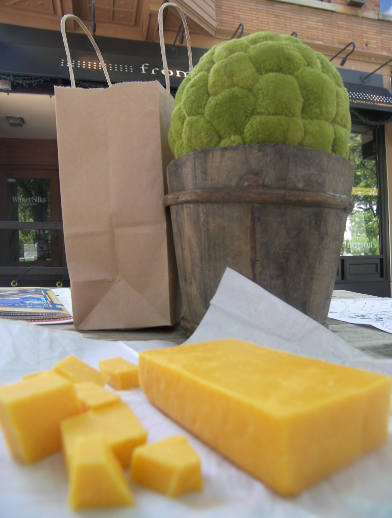 A block of Colby cheese that has been cut into cubes sitting on a table outside.