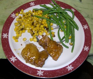 Chicken thighs with corn and green beans on a winter themed plate.
