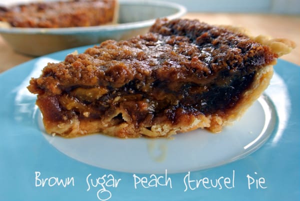 A slice of pie sitting on a blue and white plate with the whole pie in the background. On the bottom the words "Brown Sugar Peach Streusel Pie" appear.