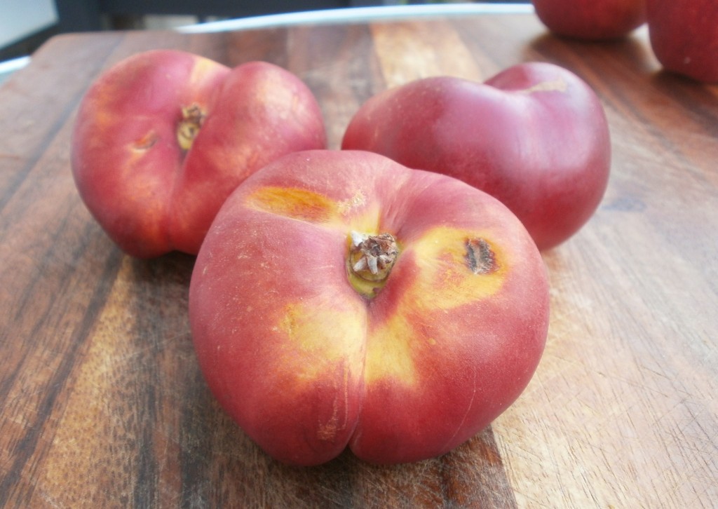 3 Donut nectarines on a wood cutting board.