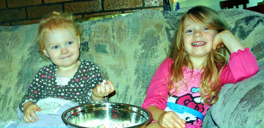 Two kids enjoying Tiny But Mighty Popcorn while sitting on the couch.