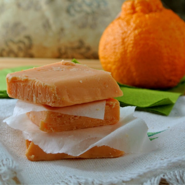 Sumo Citrus Fudge piled up sitting on a table with a Sumo behind it.