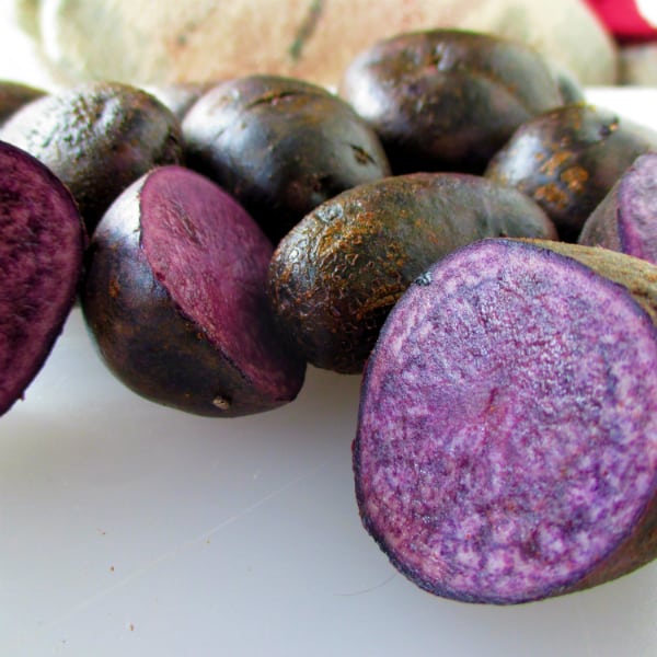 Purple potatoes that have been sliced open to show the purple interior.