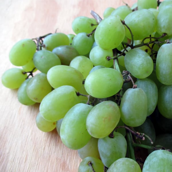 A bunch of green Cotton Candy Grapes from Mexico sitting on a wood board.