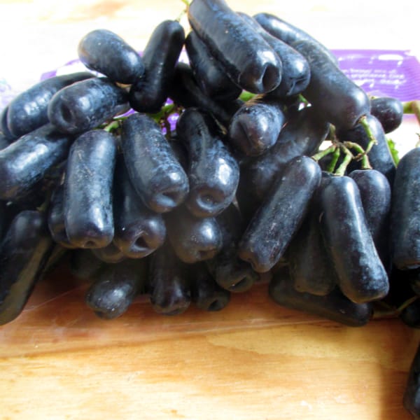 A close up of Moon Drops Grapes sitting on a wood board.