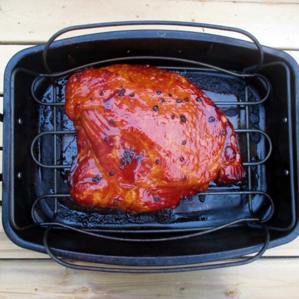 Kirkland Master Carve Boneless Ham sitting on a rack in a KitchenAid black roasting pan