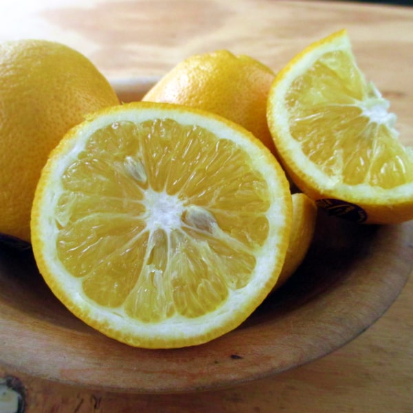 Lemonade Lemon cut open on a wood board with whole lemons in the background