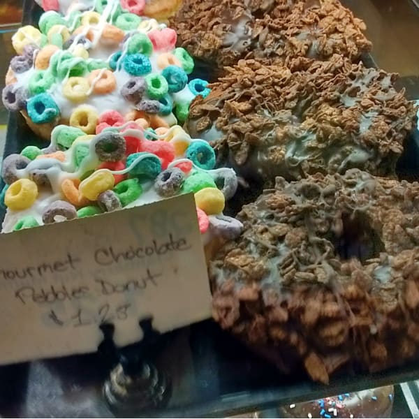 Gourmet donuts with cereal on top.