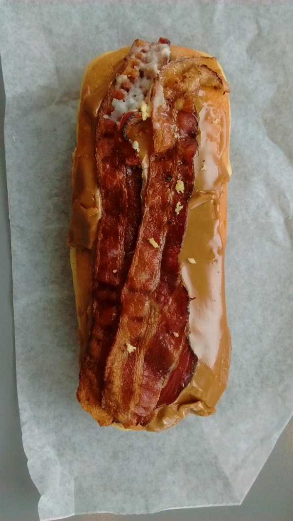A long john donut with maple icing and 2 strips of bacon!