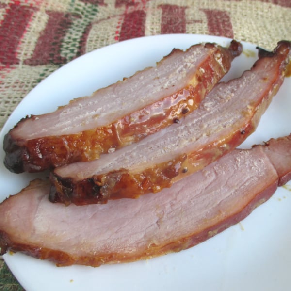 Dijon Mustard-Brown Sugar Glaze on a  Kirkland Master Carve Ham slices on a white plate on top of burlap.