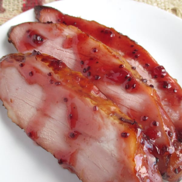 Slices of Kirkland Master Carve ham arranged on a white platter covered in a Homemade Red Currant Glaze