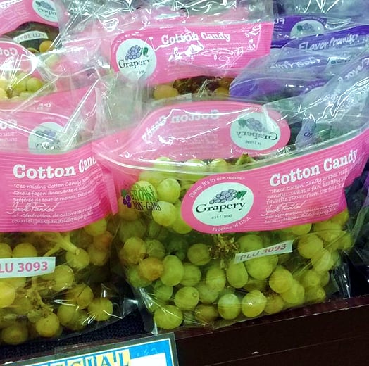 Bags of Cotton Candy grapes sitting on a grocery store display