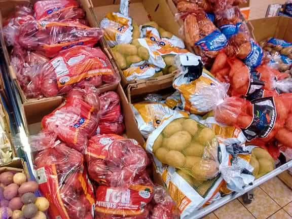 Bags of red and yellow potatoes at a grocery store.