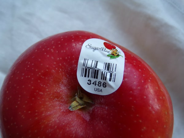 A single Sugar Bee apple with the PLU sticker featuring a cartoon bee on it.