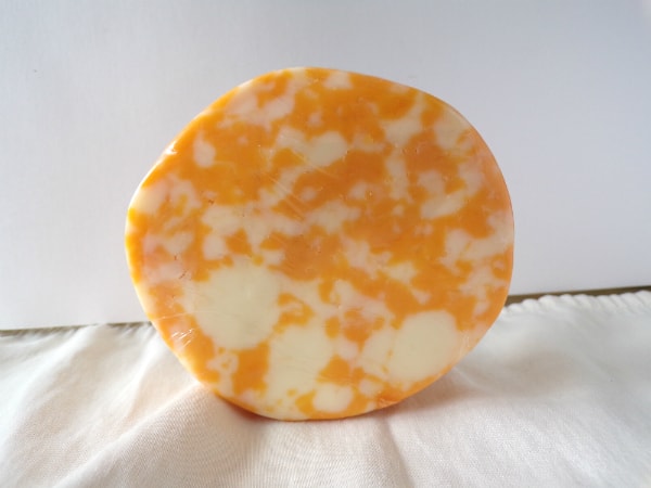 A round circle of Colby Jack cheese in front of a white background. 