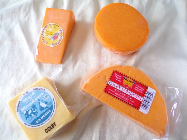 4 different types of Colby cheese that are different shapes and colors sitting on a white towel.