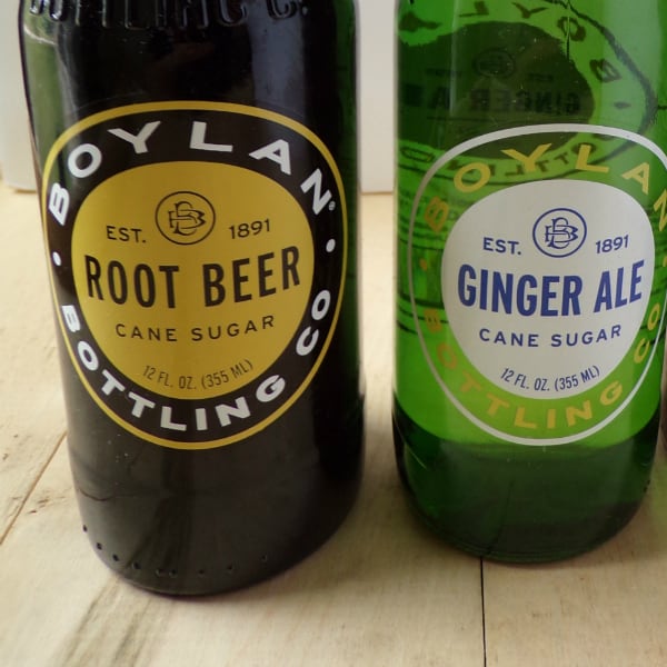 A bottle of root beer next to a bottle of ginger ale.