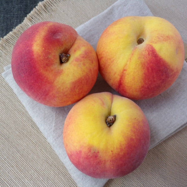 Scarlet Prince peaches in a set of three on top of two different brown colored towels.