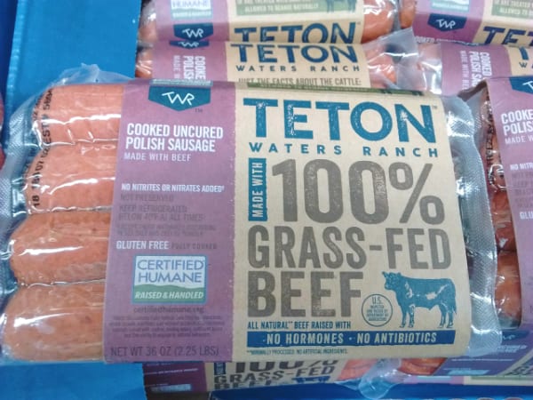 Teton Waters Ranch 100% Grass Fed Beef Uncured Polish Sausage in a vacuum sealed package with paper label surrounding it.