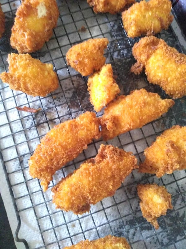 Finished fish sticks sitting on a cooling rack to drain off excess oil. A paper towel is underneath