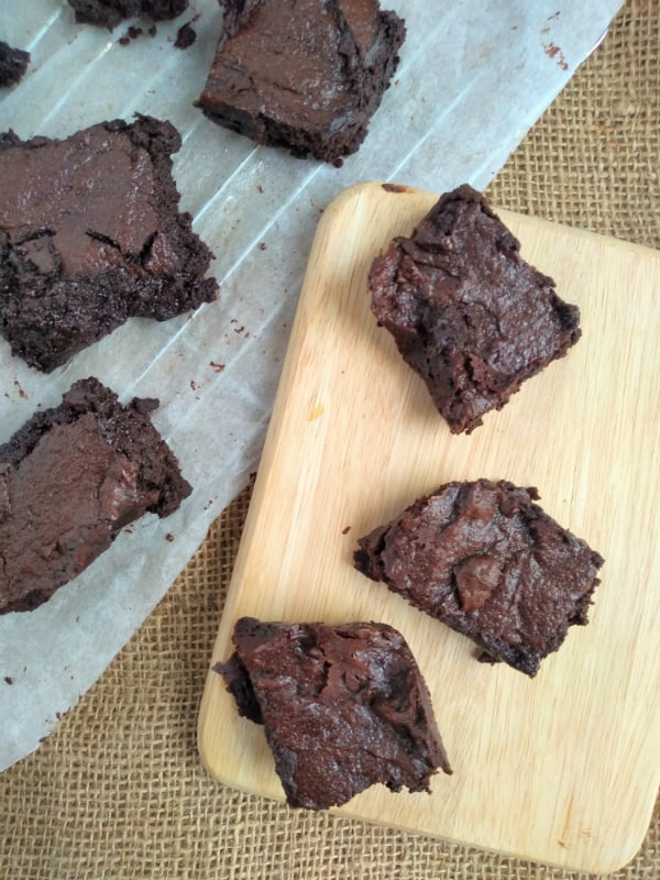 Brownies on a cutting board and a cooling rack covered with parchment paper.