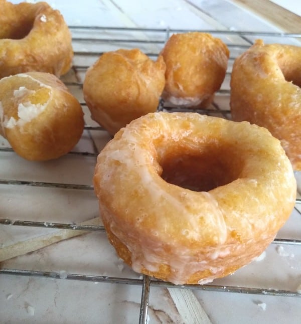 Alton Brown's Biscuit Donuts (called Bonuts) with a vanilla glaze on them, cooling on a metal rack. 