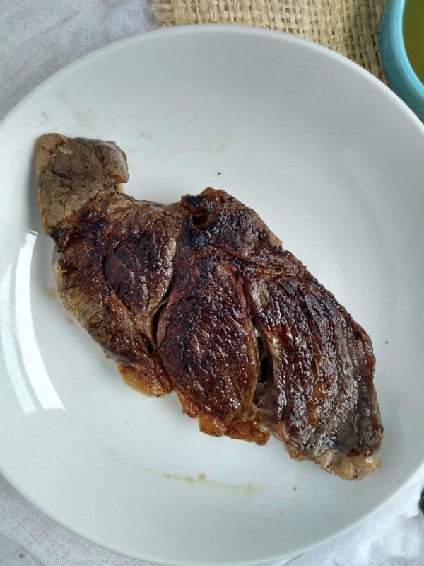 A seared sous vide chuck eye steak on a white plate.