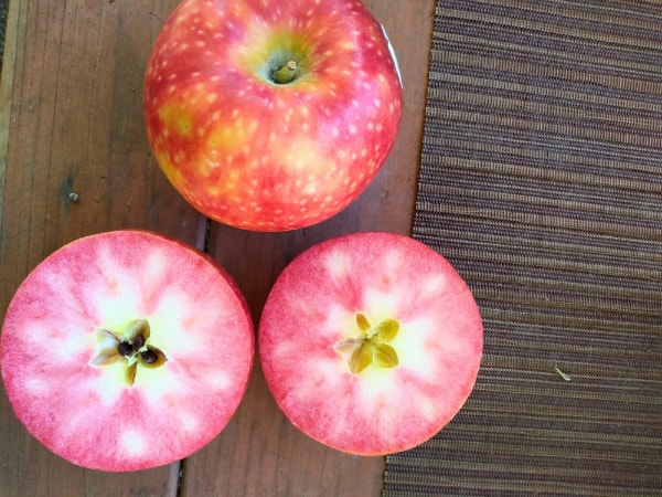 Lucy Rose apples with one cut open to show red inferior. 