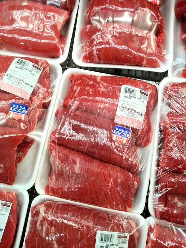 Flank steak at Costco in white packaging wrapped in plastic in a refrigerated case