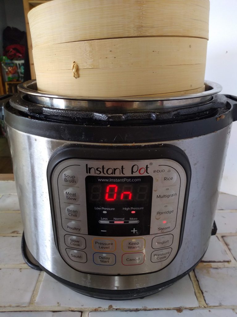 Instant Pot with a bamboo steamer on top of it