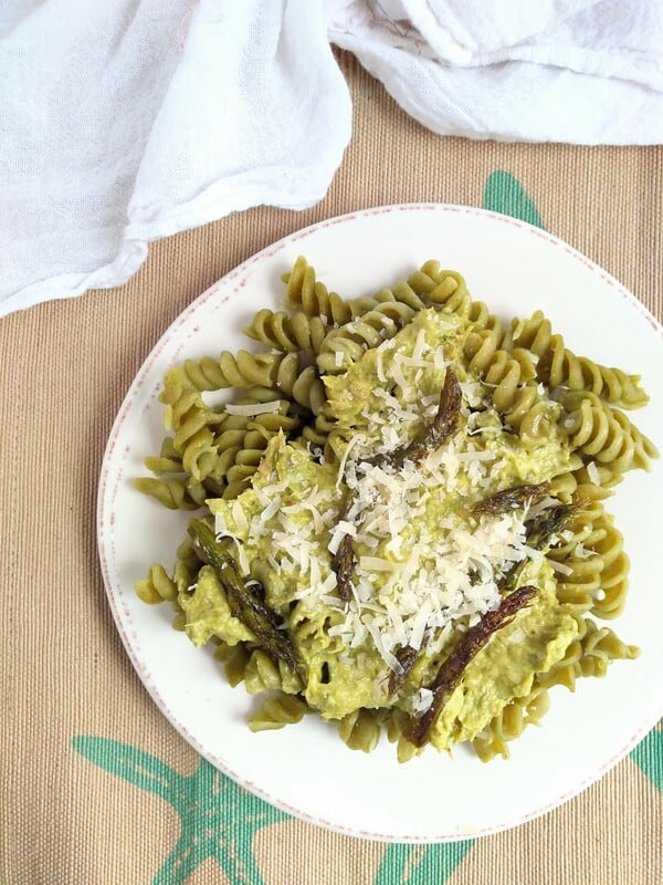 Seaweed pasta topped with asparagus pesto on a plate with a place mat underneath
