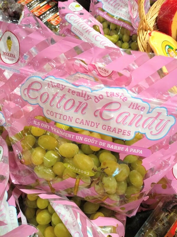 A display of green colored Cotton candy grapes at the grocery store. The bags say "They really do taste like cotton candy" on them. 