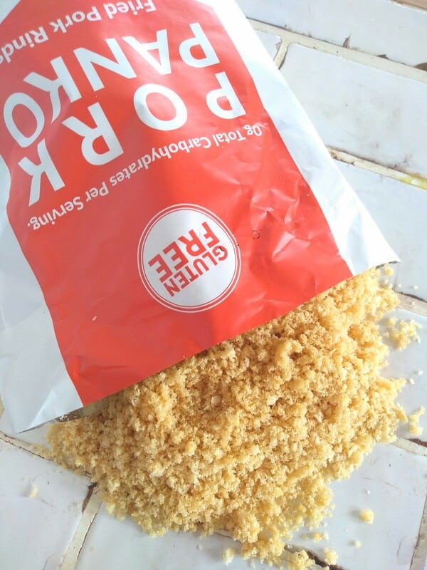 An opened bag Pork Panko Fried Pork Rinds spilling out onto a white title countertop. 