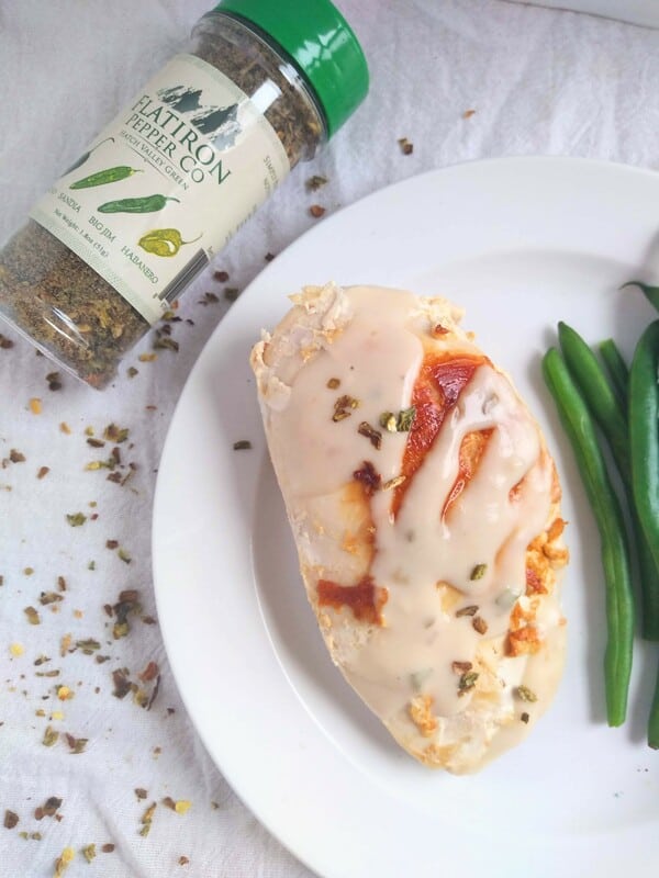 Chicken Breast with Creamy Pepper flake sauce on a white plate with a jar of Flat Iron Pepper Company Pepper Flakes.