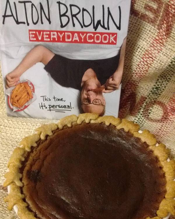 Alton Brown's Everyday Cook book on a piece of burlap with a Chocolate Cheese pie in front of it.