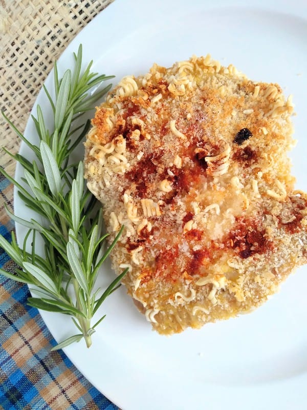 Panko and crushed ramen breaded pork chops on a plate with some rosemary