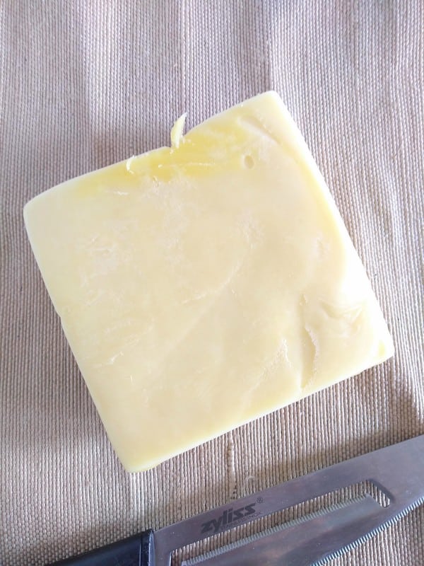 Yellowish New Zealand cheddar cheese in a block sitting on a brown table cloth