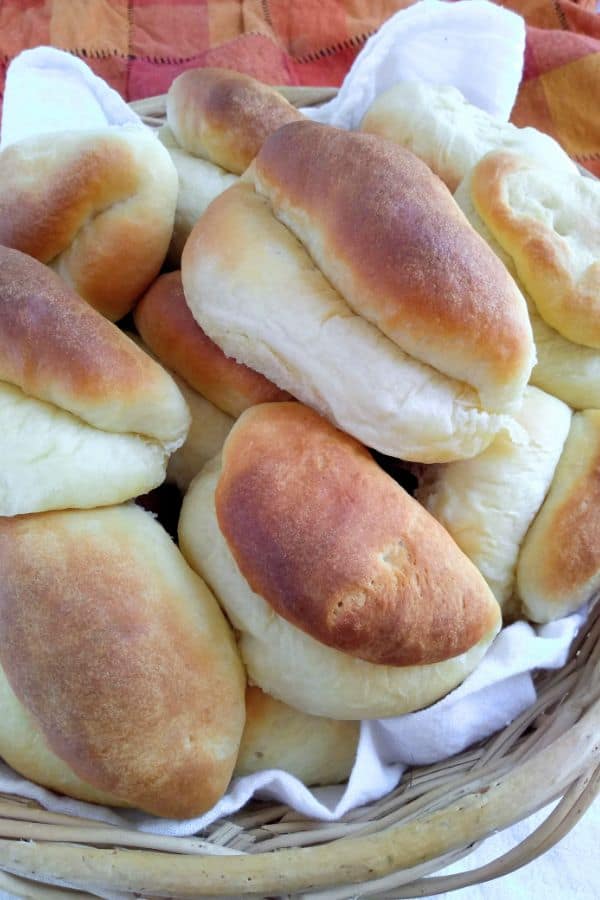 Parker House Rolls pilled up in a basket with a towel.