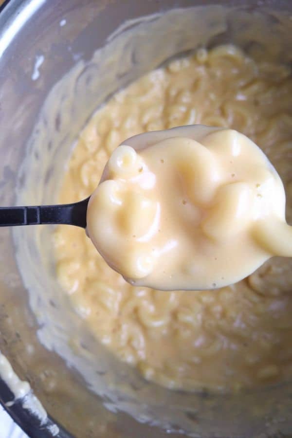 Spoon of mac and cheese from the Instant Pot over top of the pot with the rest of the mac and cheese