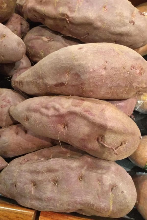 A grocery store display of Purple Sweet Potatoes that are purple inside and out.