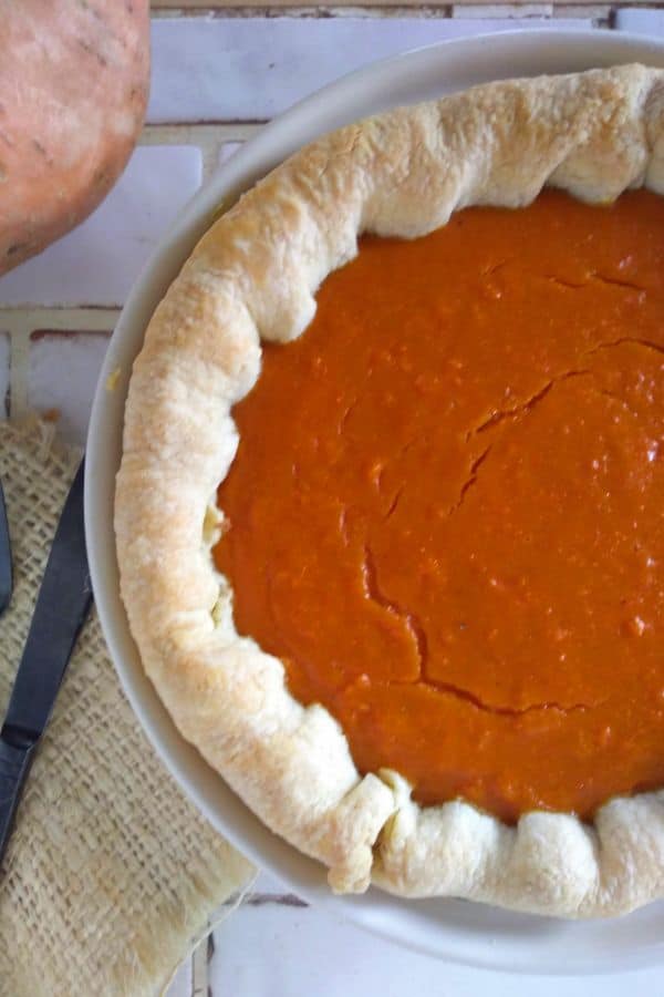 A cooked sweet potato pie is cooling on the counter top.