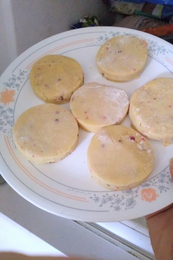 Sugar cookies coming out of the freezer on a white plate with a floral print around the edge
