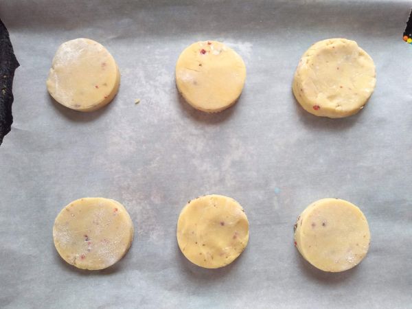 Circle shaped sugar cookies on a parchment lined sheet pan.