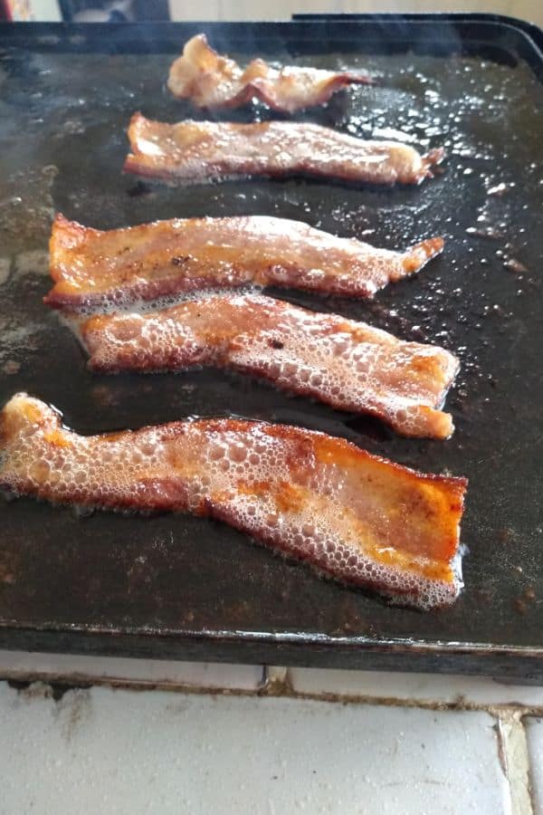 Bacon cut in half on an electric griddle