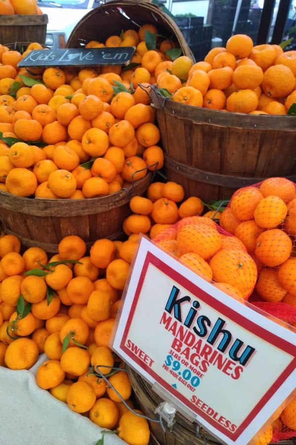 A display of Kishu mandarins loose and in bags at a farmer's market.