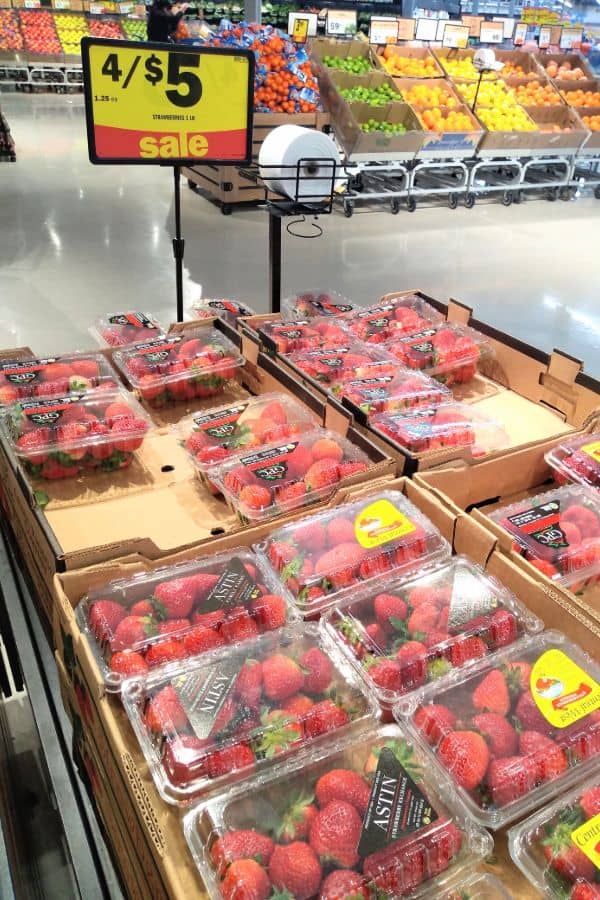 Strawberries on sale in the winter at a Meijer grocery store in Michigan. A display of the berries in their boxes with a sign that says the sale is 4 for $5.