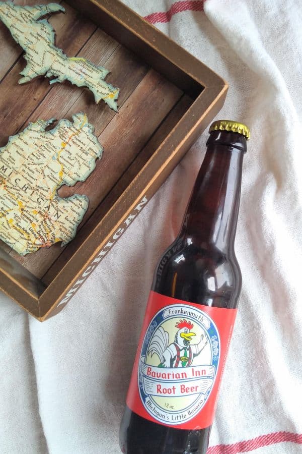 A bottle of Frankenmuth Bavarian Inn Root Beer next to a wood Michigan map.