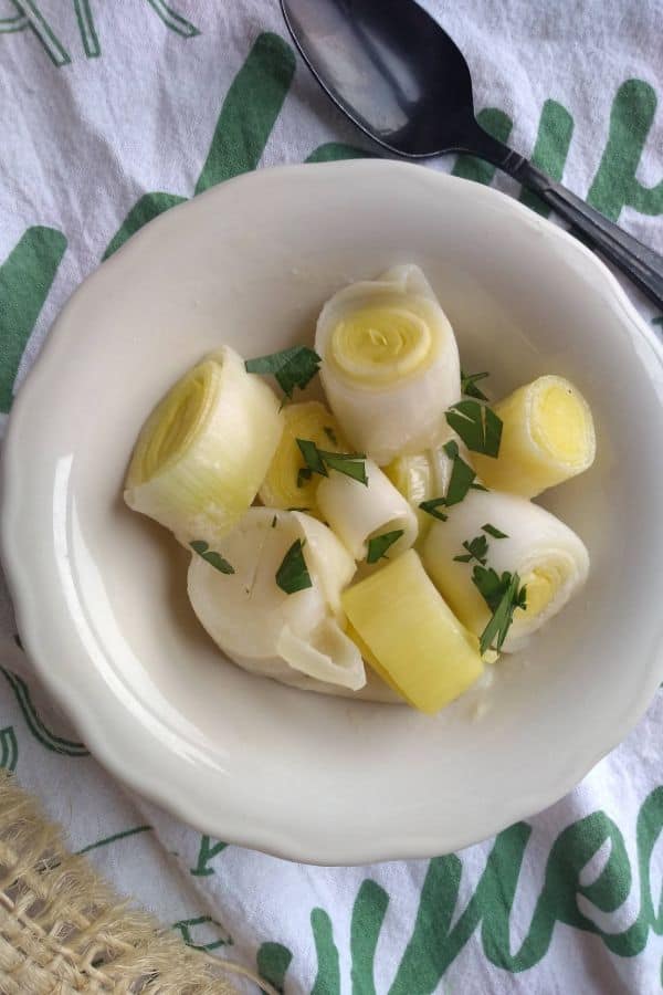 A white bowl of cut up buttered leeks.